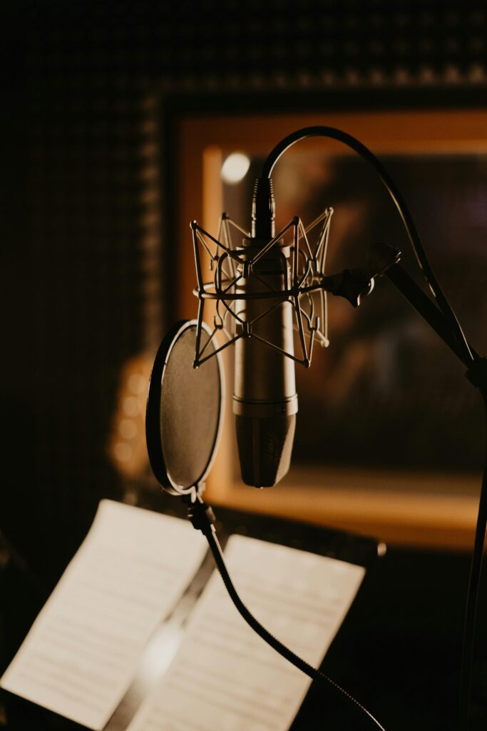 pexels-photo-4988132-4988132 Close-up of a microphone and pop filter in a dimly lit recording studio, perfect for music production.